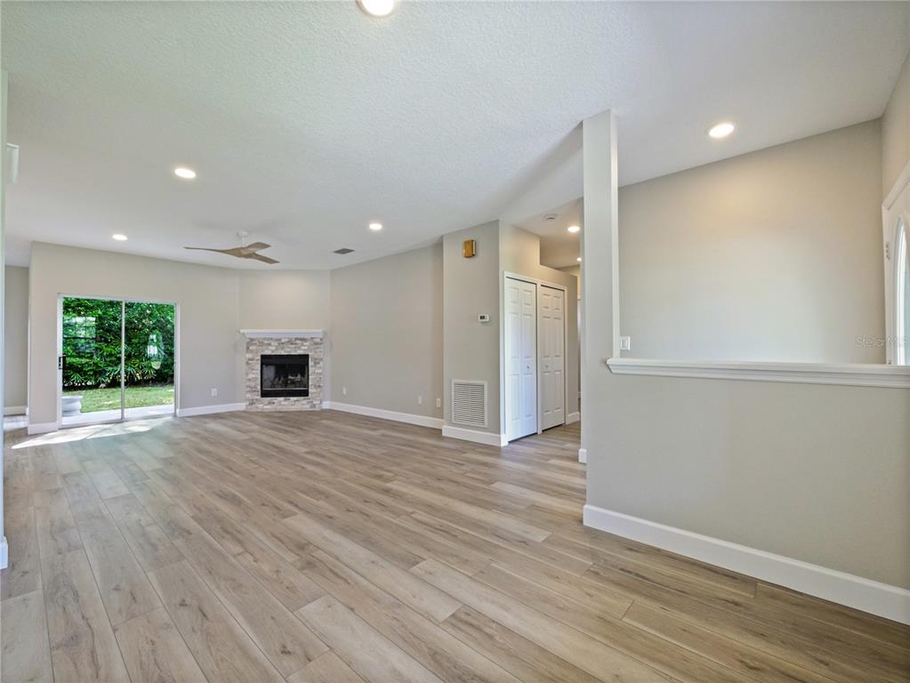 A living room with light wood-look flooring, a corner fireplace, and sliding glass doors — 1801 FORMOSA AVENUE, ORLANDO, FL