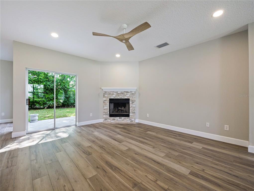 A living room features wood-look flooring, a corner stone fireplace, and sliding glass patio doors — 1801 FORMOSA AVENUE, ORLANDO, FL