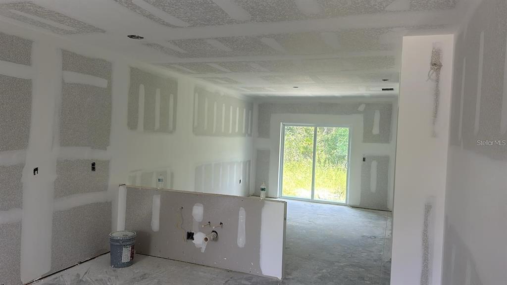 An unfinished room features drywall, a half wall with plumbing, and sliding glass doors — 17099 CARLEEN AVENUE, PORT CHARLOTTE, FL