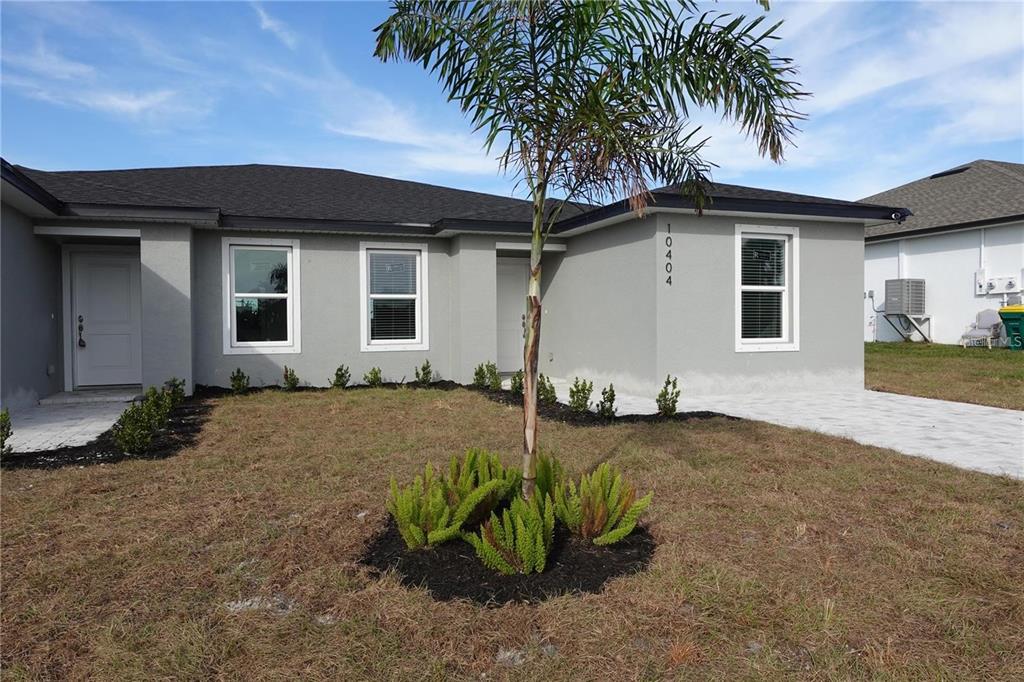 The exterior of a gray, single-story house features a palm tree and a paved driveway — 17099 CARLEEN AVENUE, PORT CHARLOTTE, FL