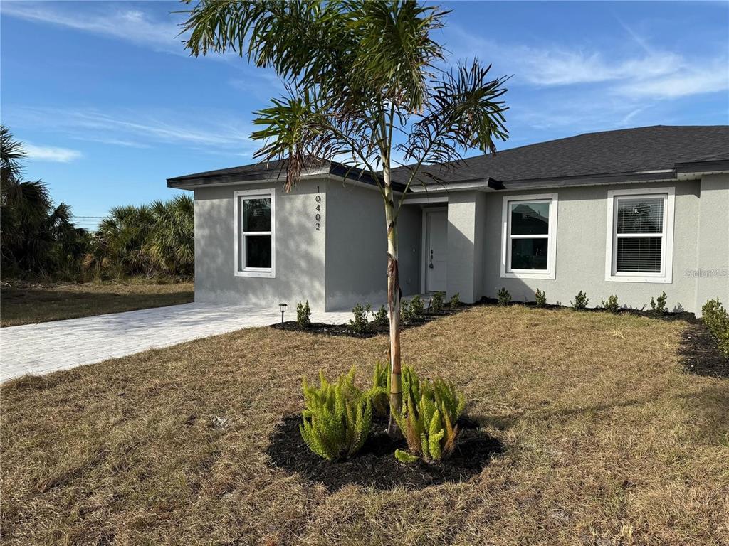 A single-story gray house with a palm tree in the front yard — 17099 CARLEEN AVENUE, PORT CHARLOTTE, FL