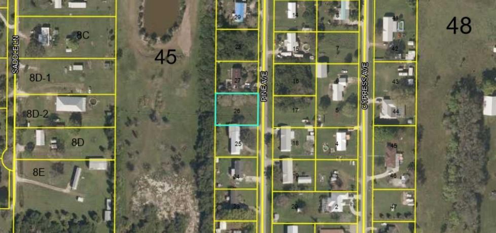 This is a satellite map showing a vacant lot highlighted in blue among residential properties — 1099 Pine Avenue, Moore Haven FL 33471, MOORE HAVEN, FL