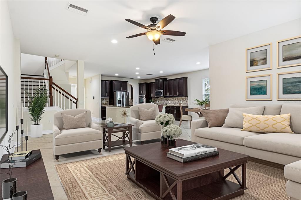 A living room with beige furniture, a dark wood coffee table, and an open kitchen — 4424 VERMILLION SKY DRIVE, WESLEY CHAPEL, FL