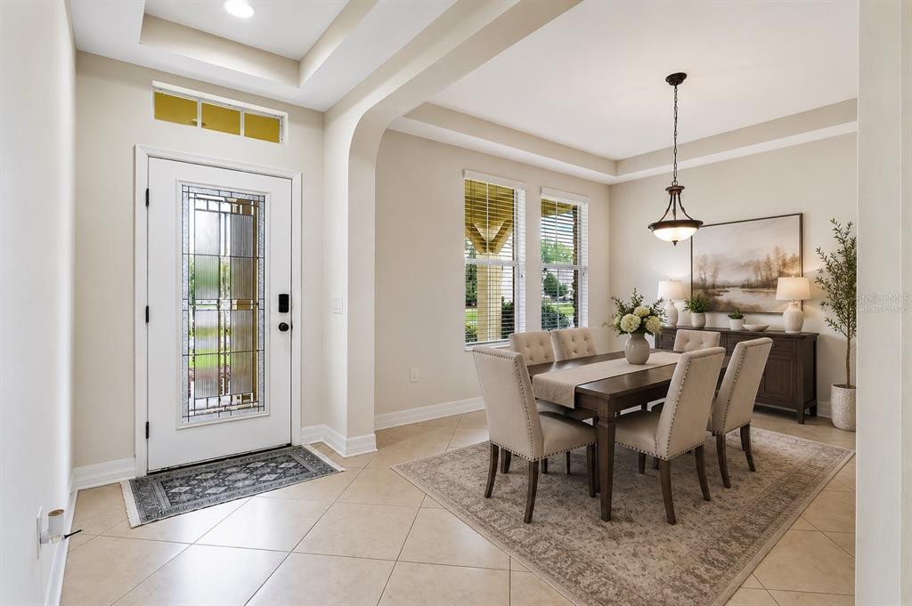 A dining room with a table, six chairs, and an adjacent entryway with a glass door — 4424 VERMILLION SKY DRIVE, WESLEY CHAPEL, FL