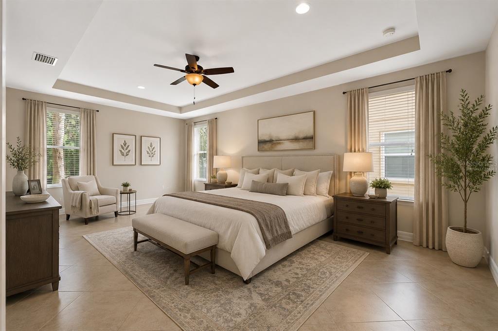 A spacious bedroom features a tray ceiling, tile flooring, a king-sized bed, and large windows — 4424 VERMILLION SKY DRIVE, WESLEY CHAPEL, FL