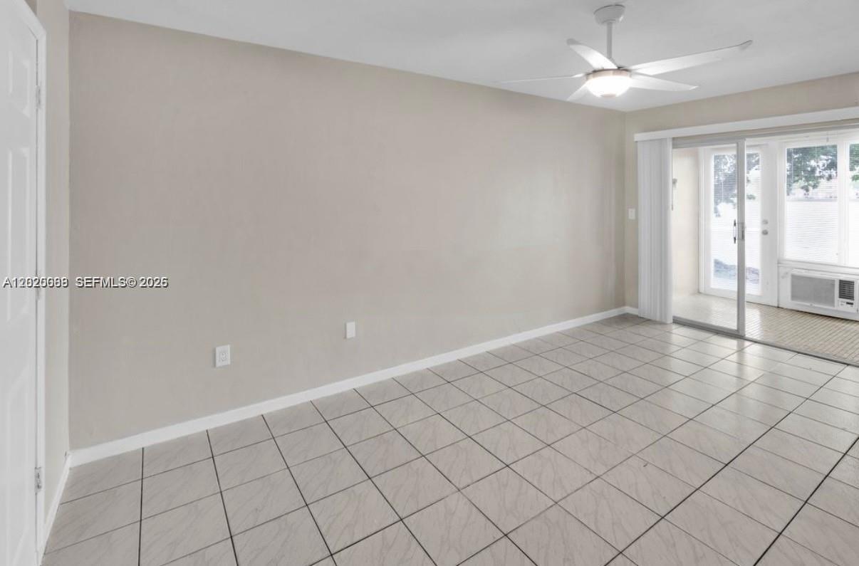 An empty room features light-colored tile flooring, a ceiling fan, and a sliding glass door — 18801 NE 2nd Ave # 1006, Miami FL 33179, MIAMI, FL