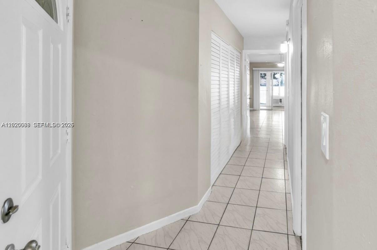 A tiled hallway leads toward a bright room with sliding glass doors — 18801 NE 2nd Ave # 1006, Miami FL 33179, MIAMI, FL