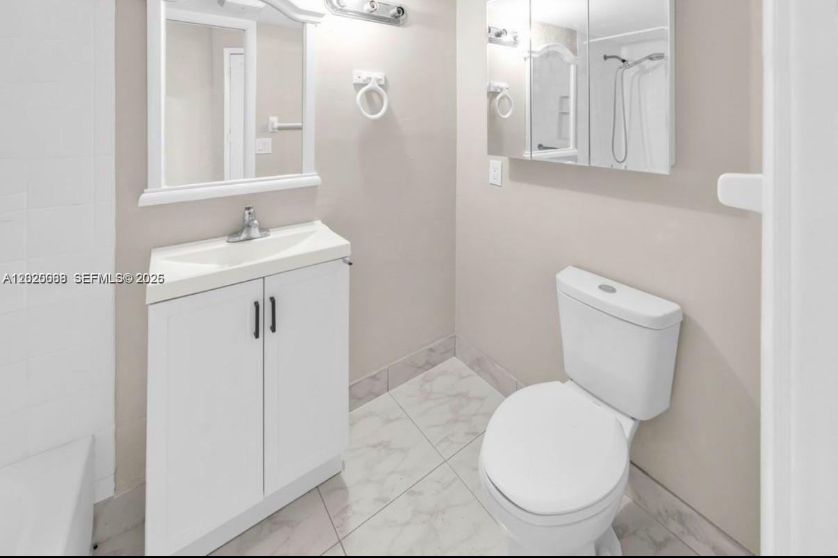 A bathroom features a white vanity, a toilet, a mirror, and light-colored tile flooring — 18801 NE 2nd Ave # 1006, Miami FL 33179, MIAMI, FL