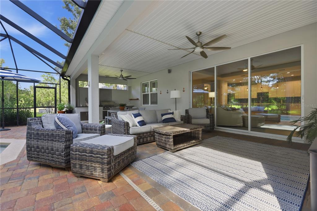 A covered outdoor patio features wicker furniture, a rug, and a ceiling fan — 108 SUFFOLK CT., DELAND, FL