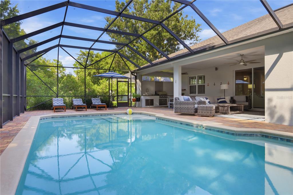 A screened-in patio features a swimming pool, outdoor kitchen, and comfortable seating area — 108 SUFFOLK CT., DELAND, FL