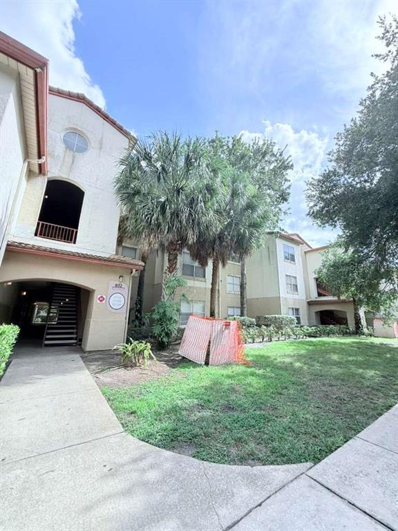 An exterior view of a multi-story apartment building with palm trees and a grassy lawn — 832 CAMARGO WAY UNIT 105, ALTAMONTE SPRINGS, FL