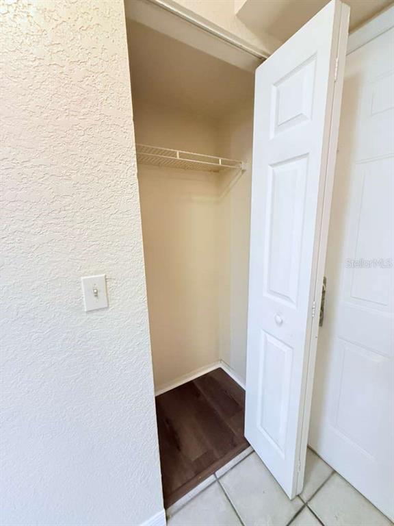 A small closet with a white bi-fold door, a wire shelf, and dark wood-look flooring — 832 CAMARGO WAY UNIT 105, ALTAMONTE SPRINGS, FL