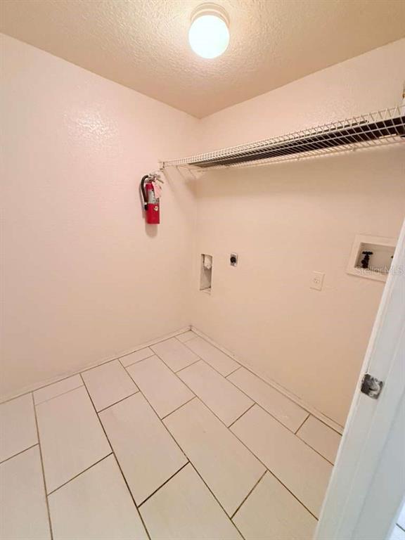 A laundry room with white tile flooring, a wire shelf, and a wall-mounted fire extinguisher — 832 CAMARGO WAY UNIT 105, ALTAMONTE SPRINGS, FL
