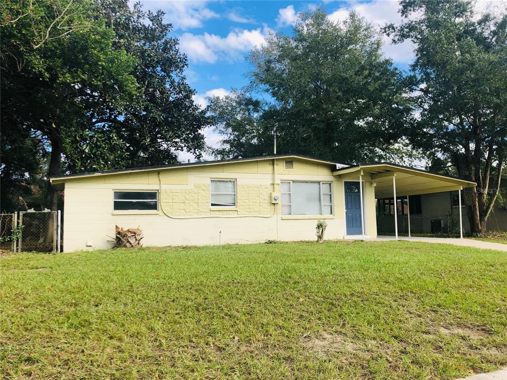 A single-story house with a light yellow exterior, a front carport, and a blue door — 240 LEE DRIVE, ORANGE PARK, FL