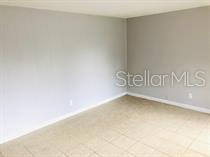 An empty room features light gray walls, beige carpeted flooring, and white baseboards — 240 LEE DRIVE, ORANGE PARK, FL