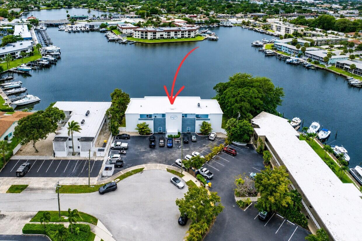 An aerial view shows a white apartment building with a parking lot and waterfront docks — 628 Southwind Circle, North Palm Beach FL 33408, NORTH PALM BEACH, FL