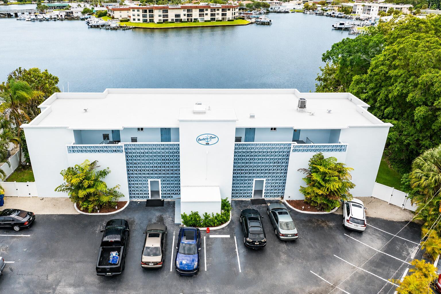 An aerial view shows a two-story white apartment building with a parking lot and waterfront — 628 Southwind Circle, North Palm Beach FL 33408, NORTH PALM BEACH, FL