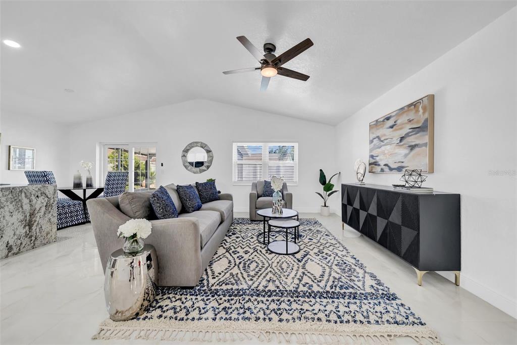 A living room features a gray sofa, a patterned rug, and a black sideboard — 2020 58TH AVENUE S, ST PETERSBURG, FL