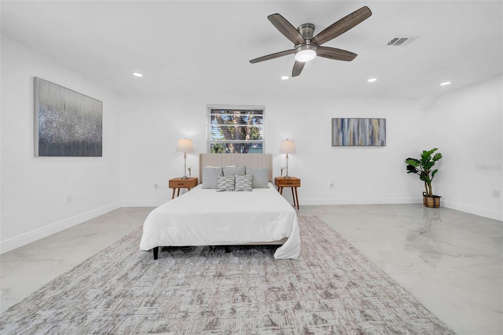 A spacious bedroom features white walls, a central bed, a ceiling fan, and tile flooring — 2020 58TH AVENUE S, ST PETERSBURG, FL