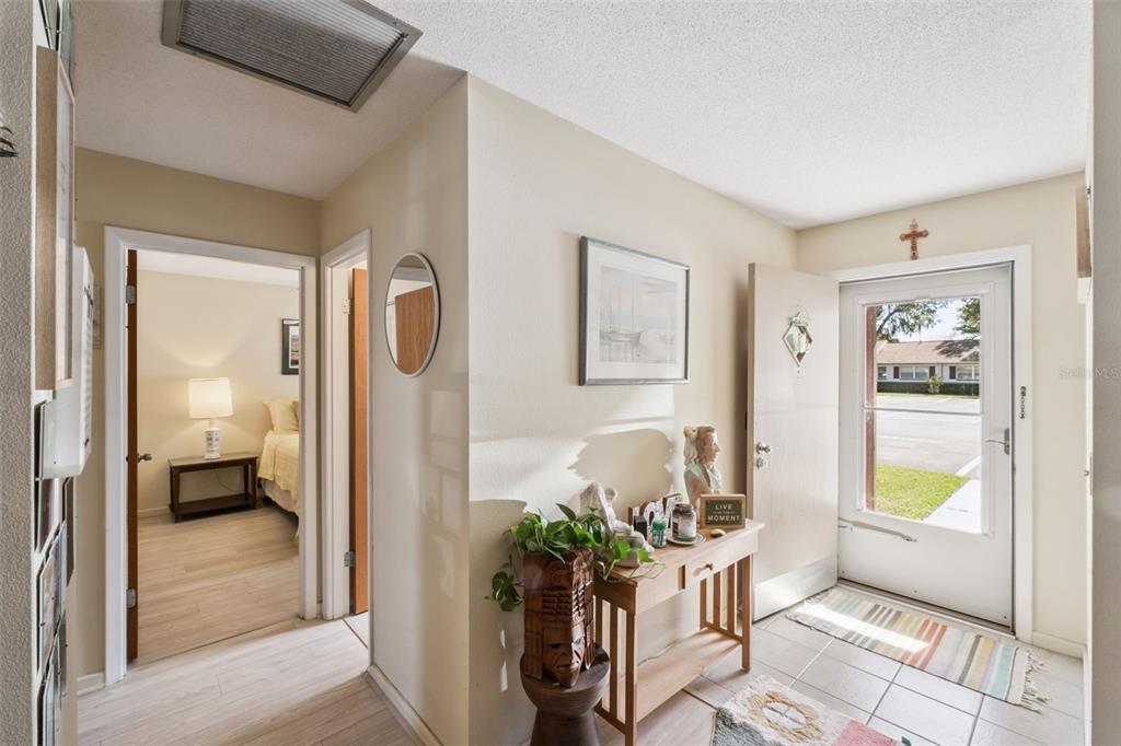 An entryway with tile flooring, a wooden console table, and a view into a bedroom — 714 E MINNESOTA AVENUE UNIT B, DELAND, FL