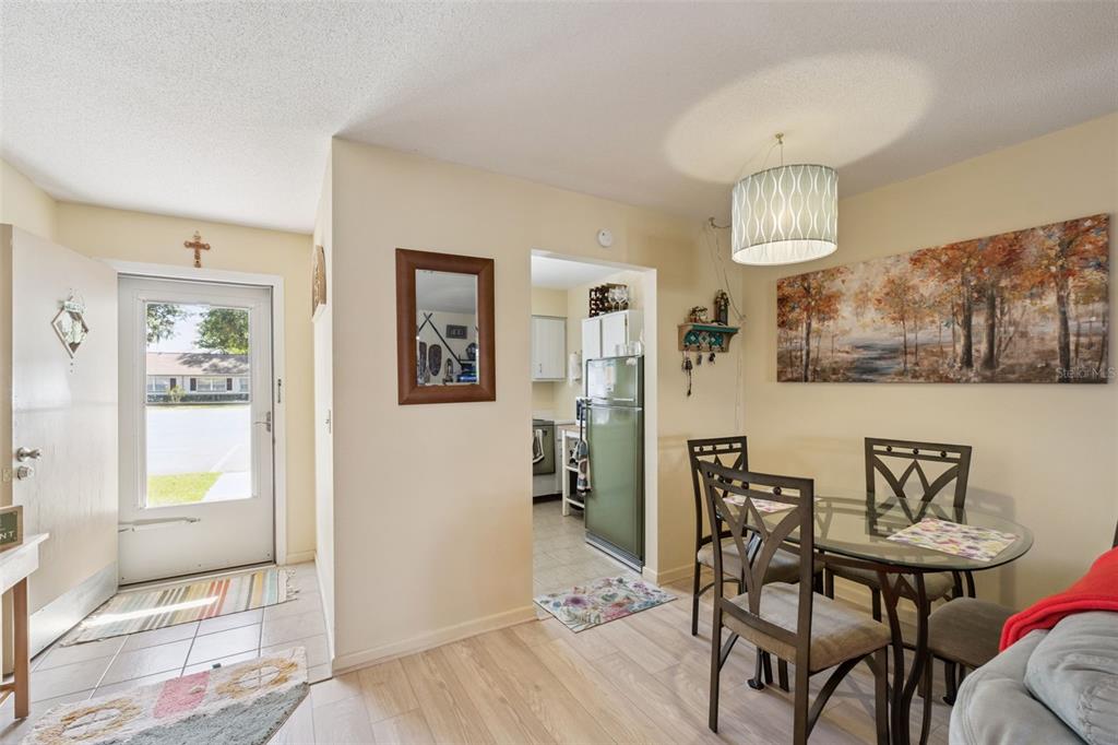 A dining area with a glass table and chairs sits adjacent to a kitchen entrance — 714 E MINNESOTA AVENUE UNIT B, DELAND, FL