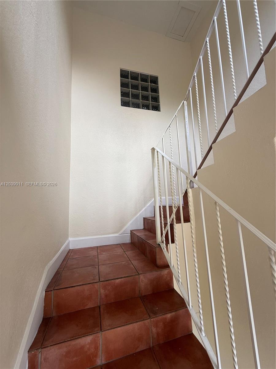 A staircase with terracotta tile steps and a white metal railing leads upward — 426 NE 77th St Rd # 4, Miami FL 33138, MIAMI, FL