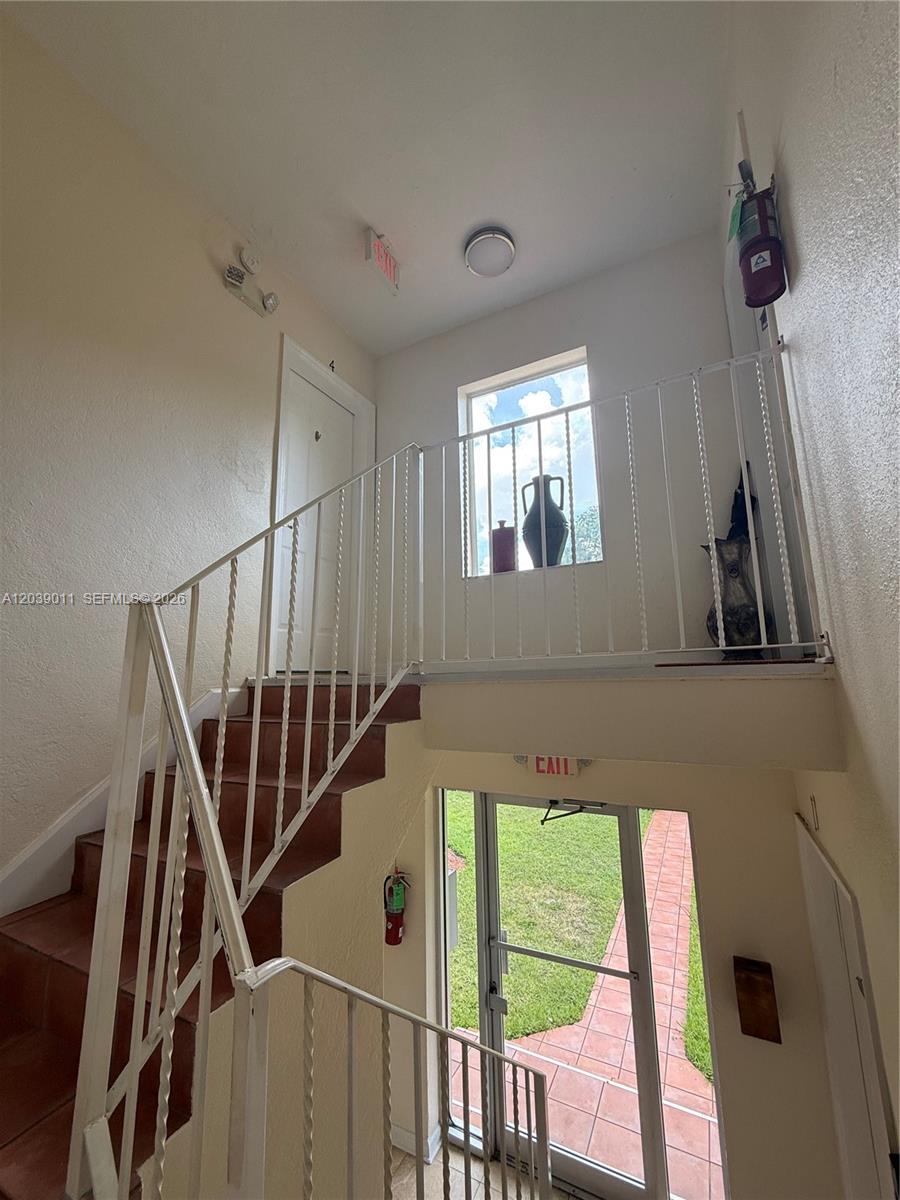 An interior staircase leads to an upper landing with a door and a window — 426 NE 77th St Rd # 4, Miami FL 33138, MIAMI, FL