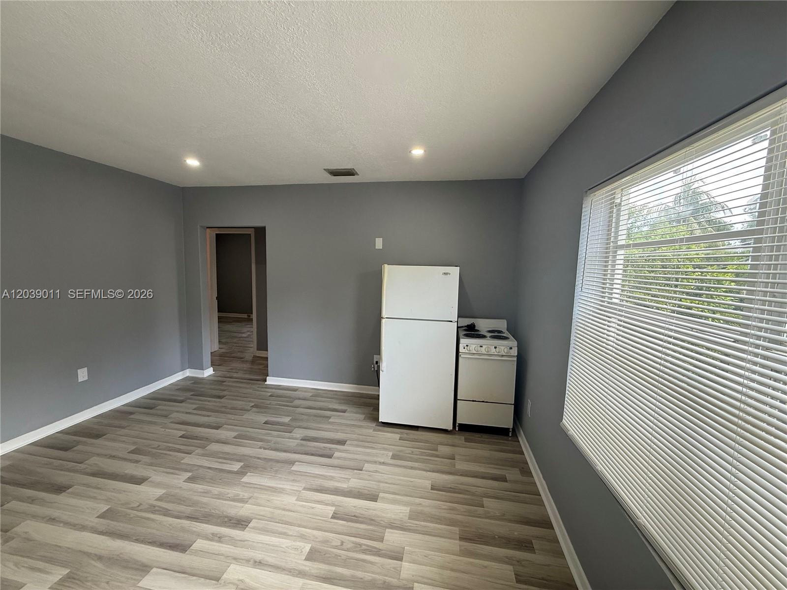 A room with gray walls, wood-look flooring, a white refrigerator, and a white stove — 426 NE 77th St Rd # 4, Miami FL 33138, MIAMI, FL