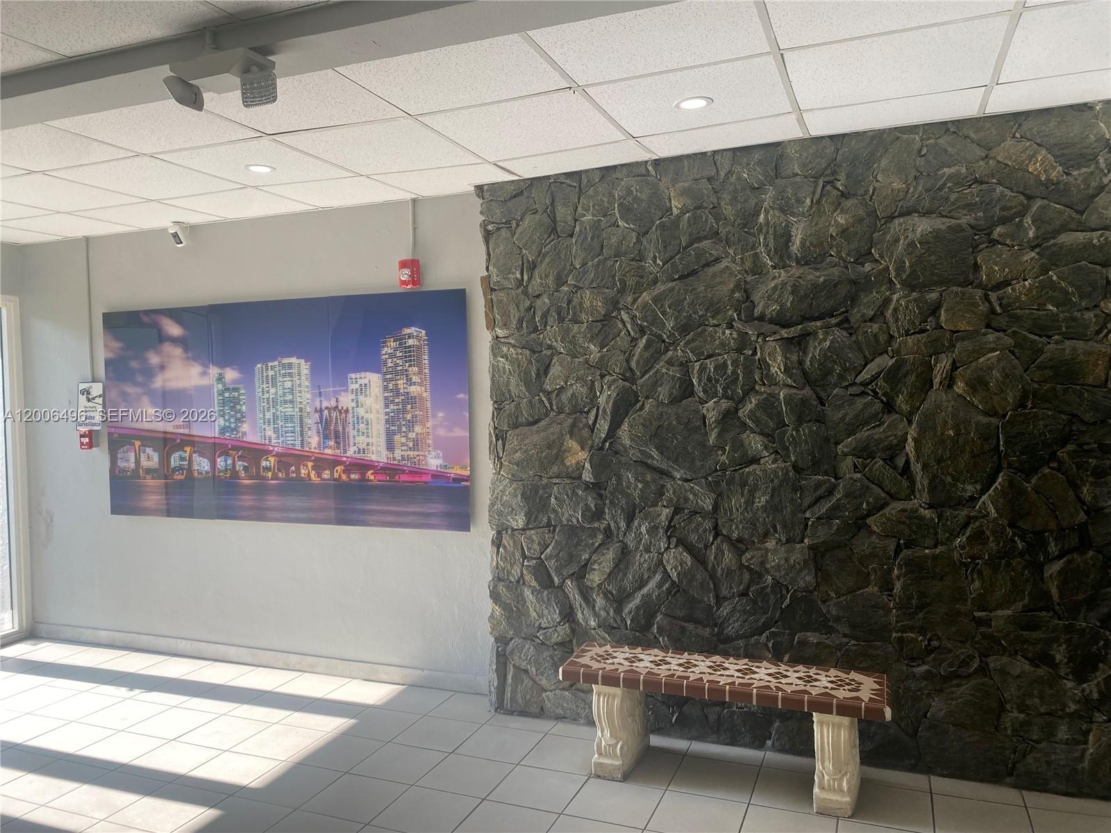 A lobby features a stone accent wall, a tiled floor, a bench, and wall art — 900 SW 84th Ave # 415D, Miami FL 33144, MIAMI, FL