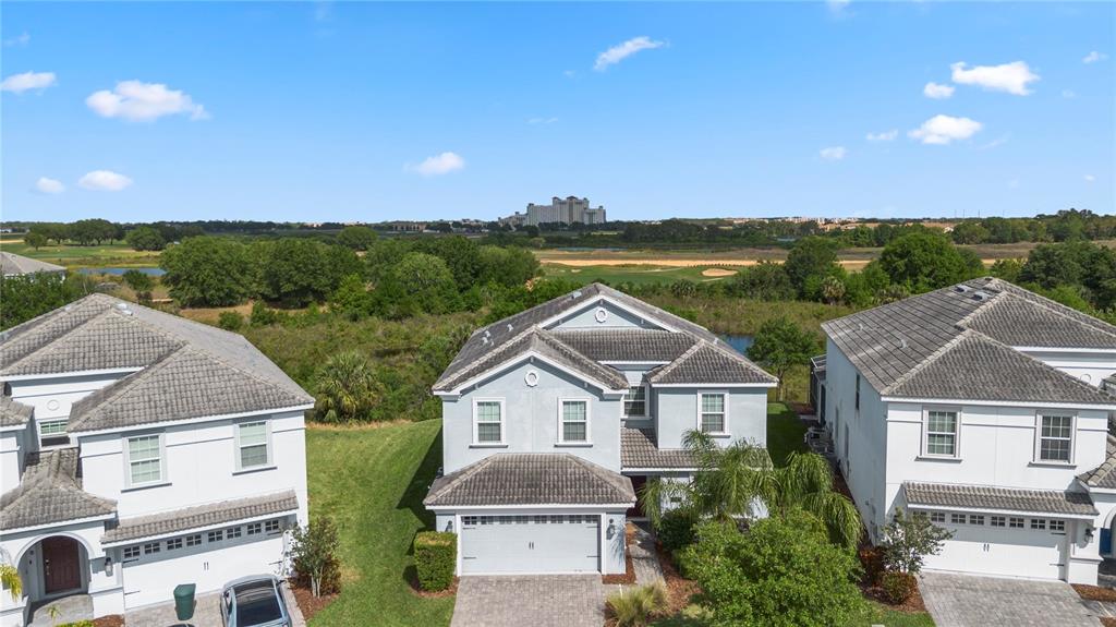 An aerial view shows three two-story houses with tiled roofs and driveways near a golf course — 1571 PALMERO WAY, DAVENPORT, FL