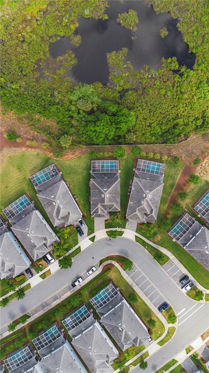 An aerial view shows a suburban cul-de-sac with houses featuring screened-in pools near a pond — 1571 PALMERO WAY, DAVENPORT, FL