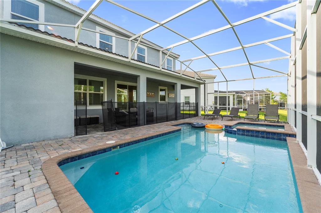A screened-in patio features a swimming pool, a hot tub, and a paved deck — 1571 PALMERO WAY, DAVENPORT, FL