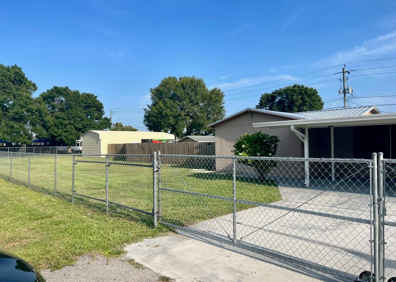 A chain-link fence encloses a grassy yard with a house and a detached metal shed — 1019 NW 2nd Street, Okeechobee FL 34972, OKEECHOBEE, FL