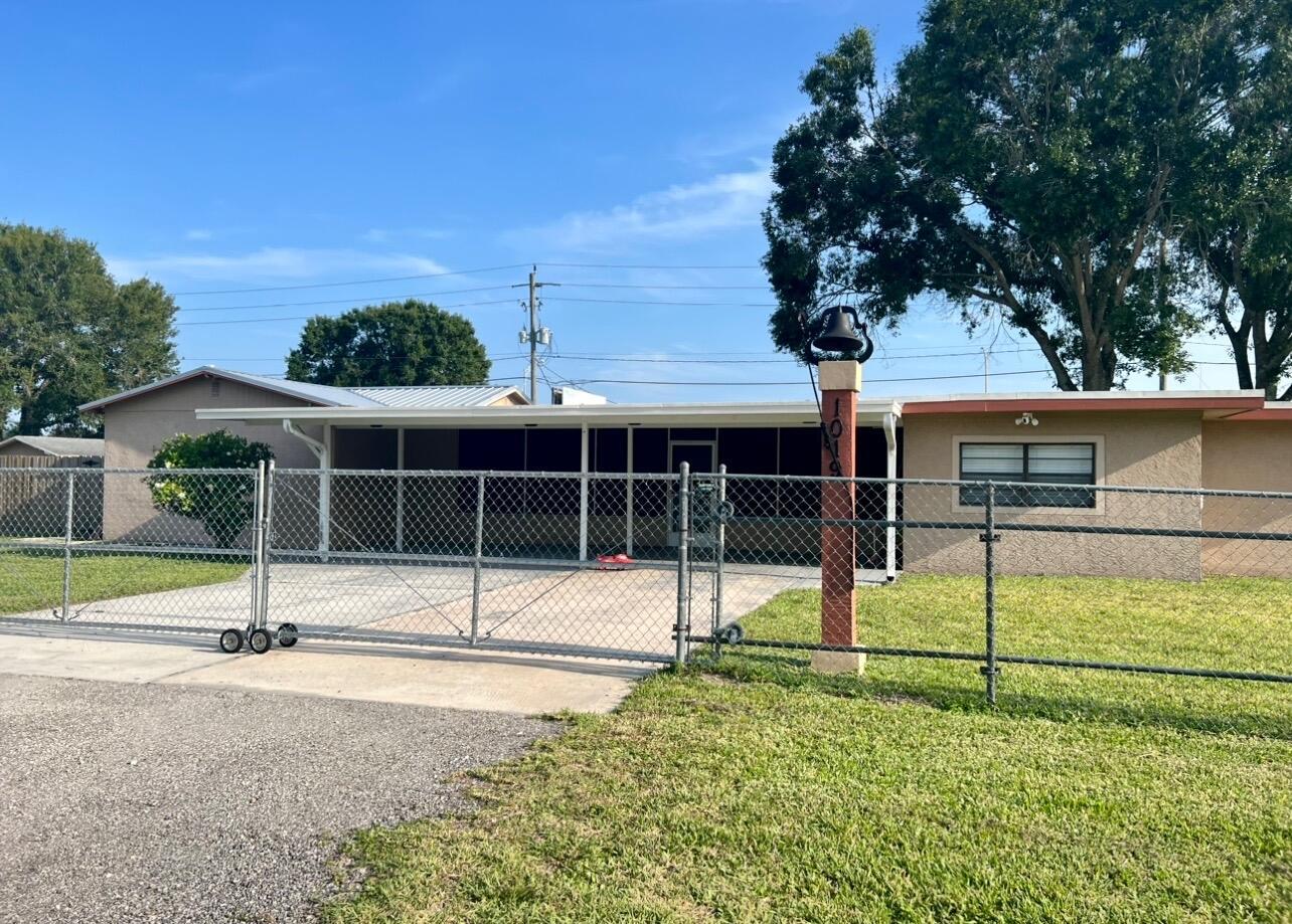 A single-story house with a carport, chain-link fence, and a decorative bell on a post — 1019 NW 2nd Street, Okeechobee FL 34972, OKEECHOBEE, FL