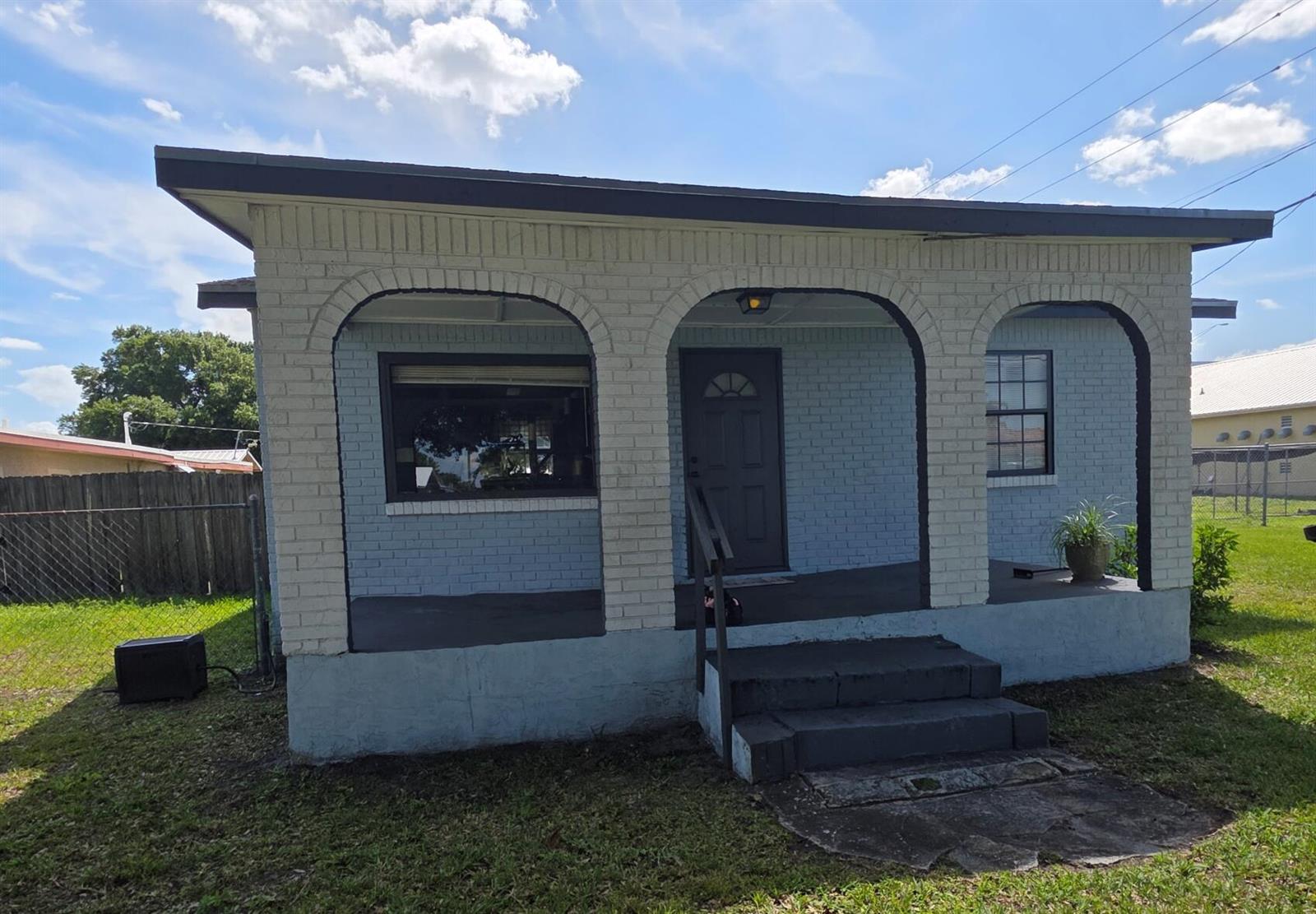 A single-story house features a covered front porch with three brick arches and steps — 1019 NW 2nd Street, Okeechobee FL 34972, OKEECHOBEE, FL