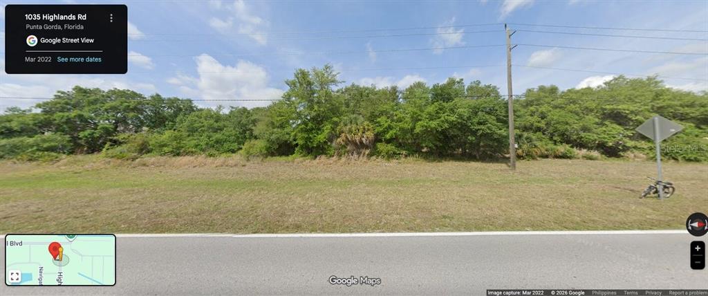 A vacant, grassy lot with dense trees and a utility pole along a paved road — 1035 HIGHLANDS ROAD, PUNTA GORDA, FL