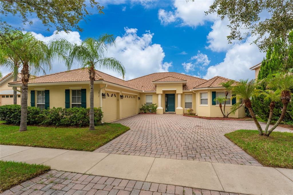 A single-story house with a tiled roof, beige stucco exterior, and a paved driveway — 3817 GOLDEN FEATHER WAY, KISSIMMEE, FL