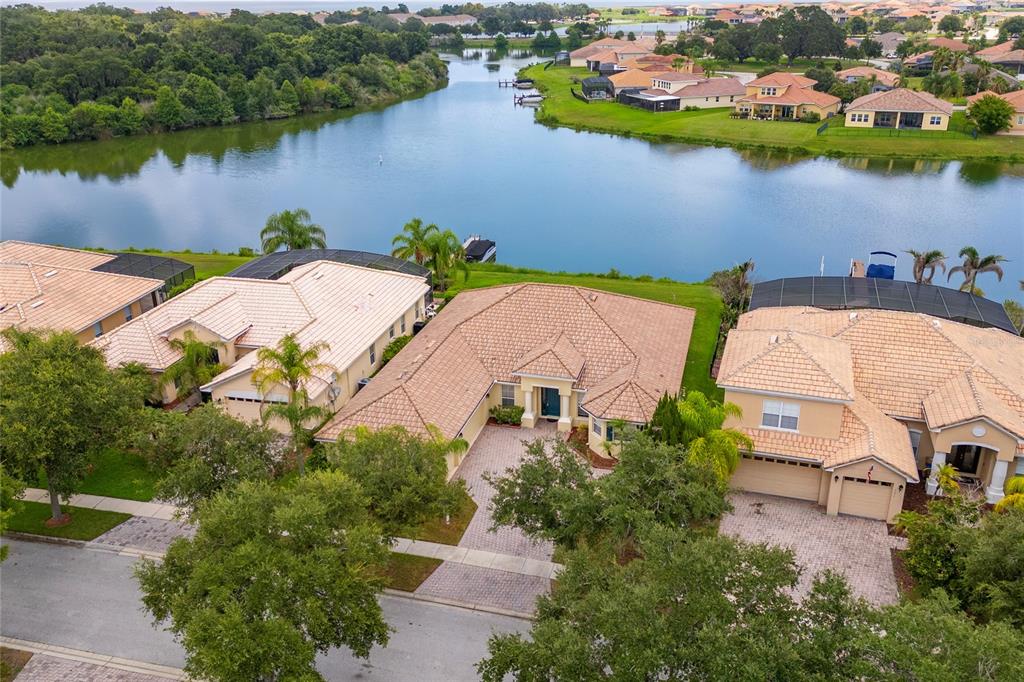 An aerial view of a suburban house with a tiled roof and a waterfront backyard — 3817 GOLDEN FEATHER WAY, KISSIMMEE, FL