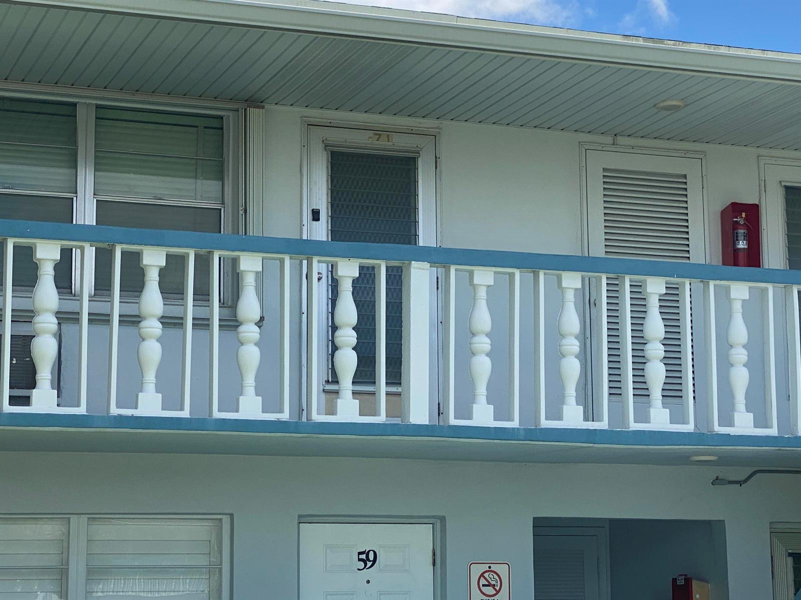 An exterior view of a building with a balcony featuring white balusters and blue railings — 71 Berkshire # 71, West Palm Beach FL 33417, WEST PALM BEACH, FL