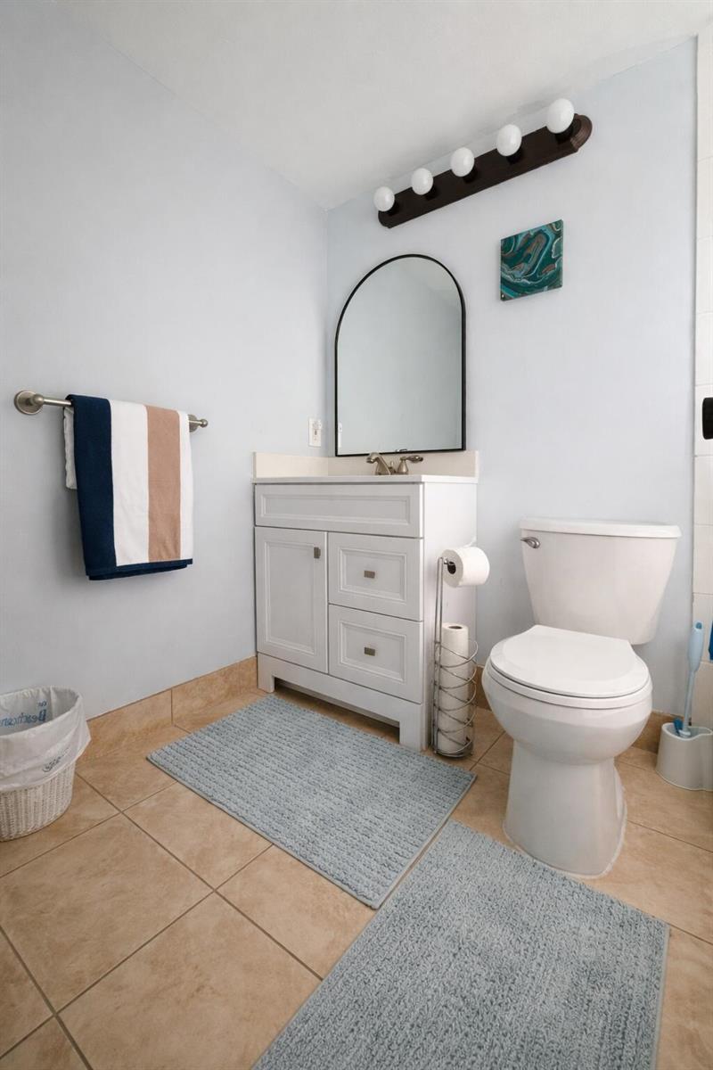 A bathroom features a white vanity, an arched mirror, a toilet, and light blue walls — 315 Tilford O # 315, Deerfield Beach FL 33442, DEERFIELD BEACH, FL