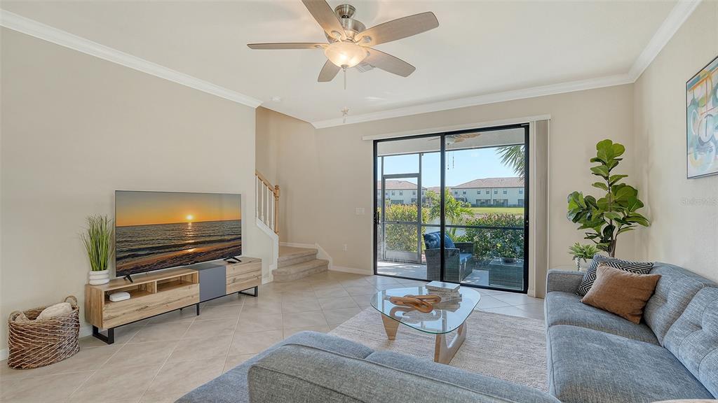 A living room features a television, a gray sofa, a glass coffee table, and sliding doors — 20223 LAGENTE CIRCLE, VENICE, FL