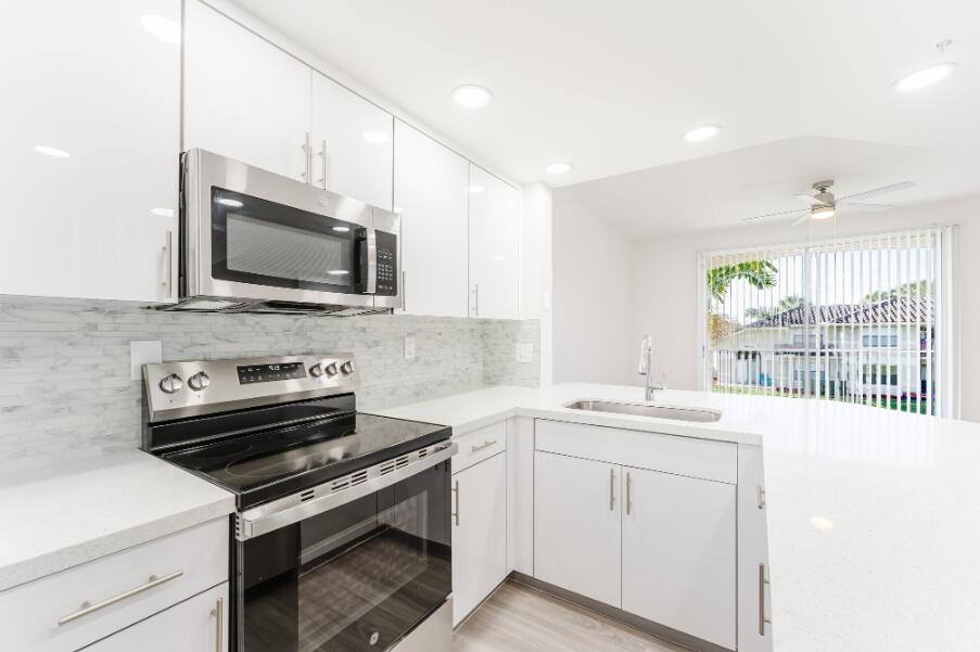 A modern kitchen features white cabinets, stainless steel appliances, and a white quartz countertop — 20889 Saint Andrews Boulevard, Boca Raton FL 33433, BOCA RATON, FL