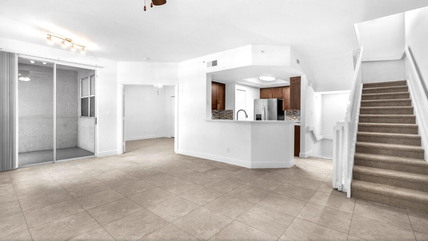 An open-concept living area features tile flooring, a kitchen with a breakfast bar, and stairs — 20889 Saint Andrews Boulevard, Boca Raton FL 33433, BOCA RATON, FL
