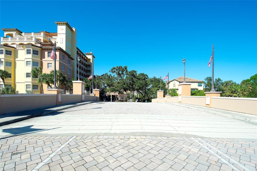 A paved driveway leads toward a large multi-story building under a clear blue sky — 1921 MONTE CARLO DRIVE UNIT 603, SARASOTA, FL