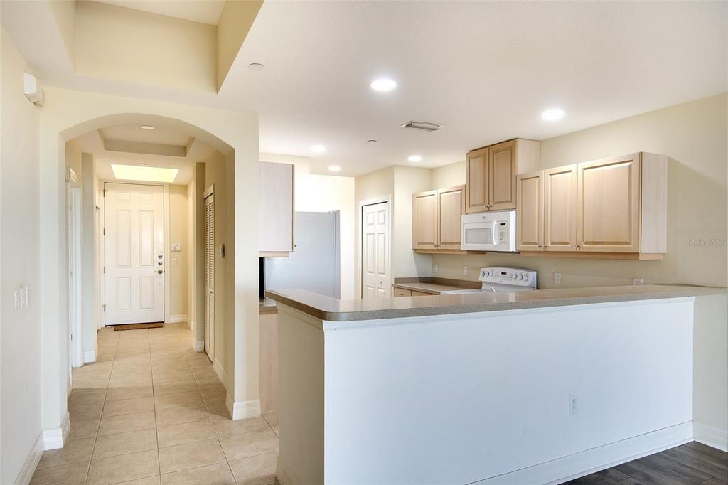 A kitchen with light wood cabinets and a breakfast bar overlooks a tiled entryway — 1921 MONTE CARLO DRIVE UNIT 603, SARASOTA, FL