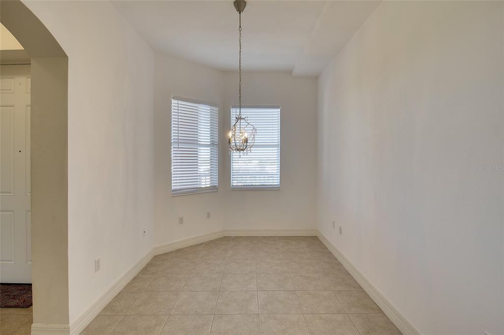 A dining area features tile flooring, white walls, two windows with blinds, and a chandelier — 1921 MONTE CARLO DRIVE UNIT 603, SARASOTA, FL