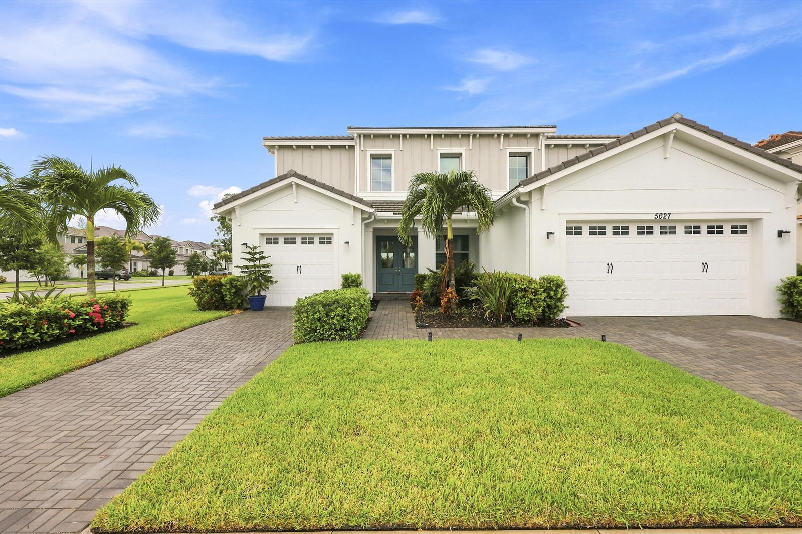A two-story house with a white exterior, two garages, and a paved driveway — 5627 Opal Drive, FL 33470, FL
