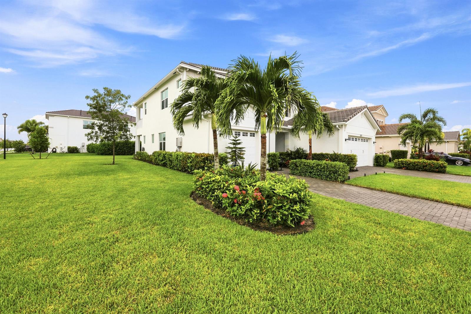 A two-story white house with a paved driveway, palm trees, and a manicured lawn — 5627 Opal Drive, FL 33470, FL