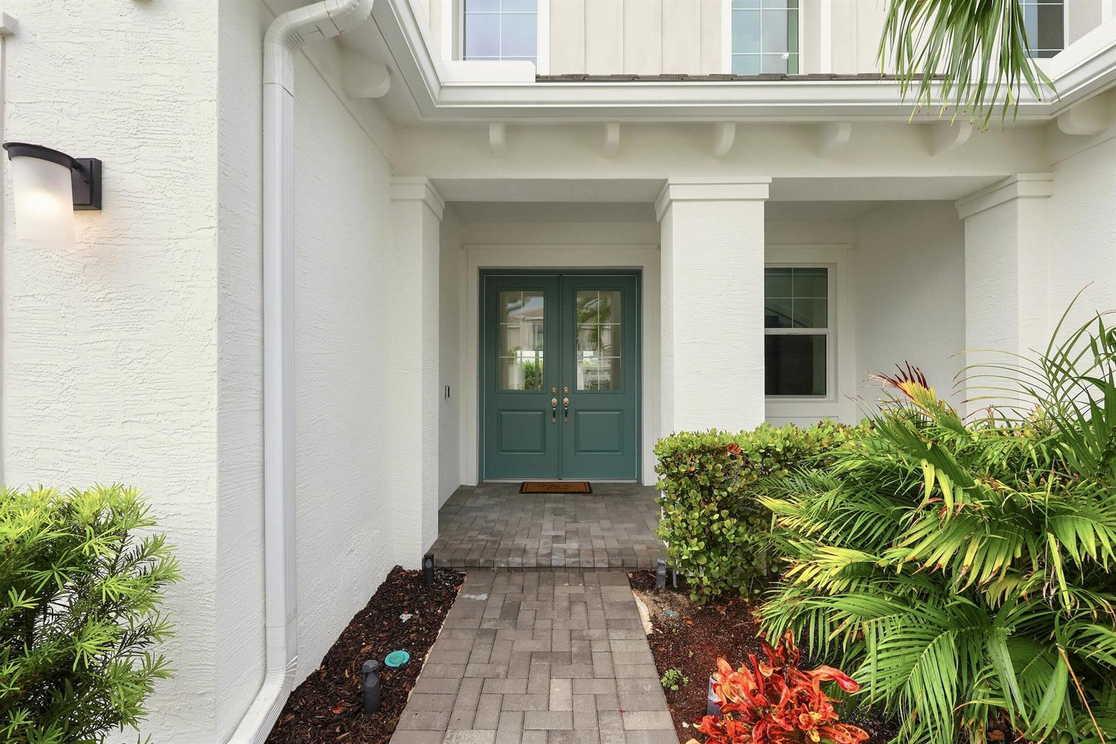 A teal double front door is centered under a covered porch with white stucco walls — 5627 Opal Drive, FL 33470, FL