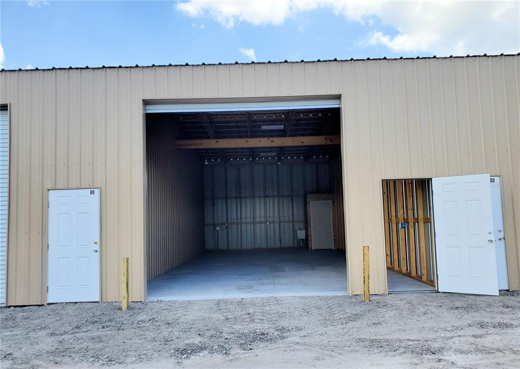 An exterior view of a metal warehouse building with a large open bay and two doors — 532 N BLUFORD AVENUE, OCOEE, FL